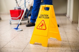 janitor with wet floor sign