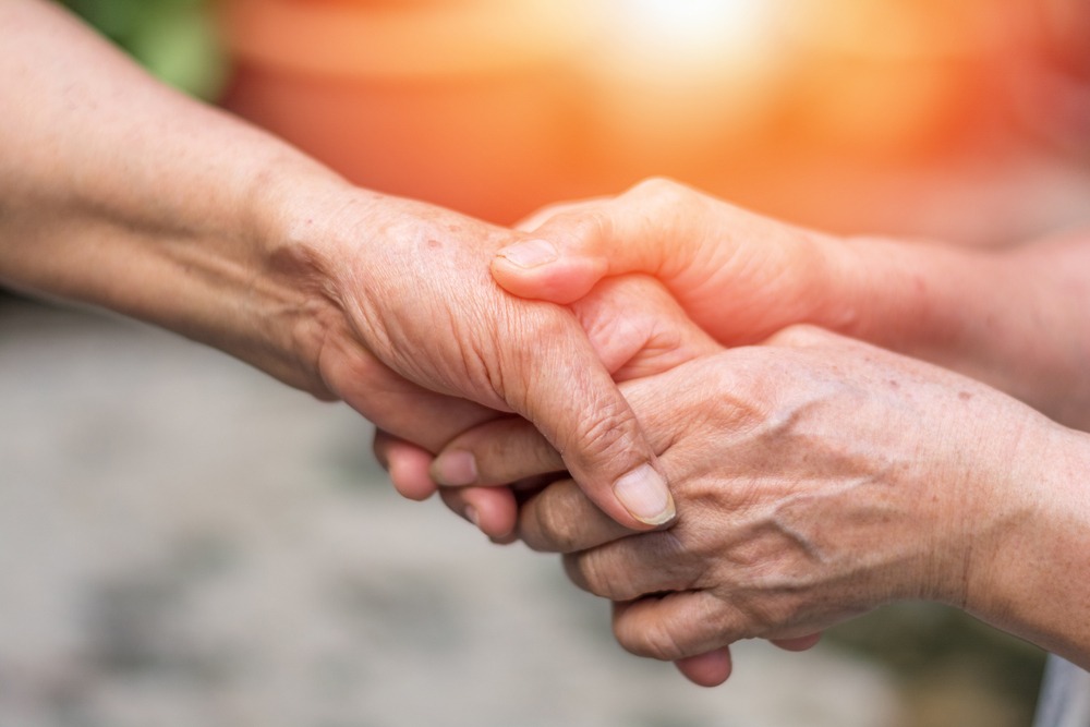 One person's older hands clasping another person's hand