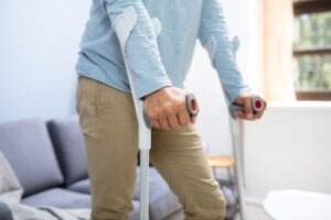 disabled man using crutches to walk at home