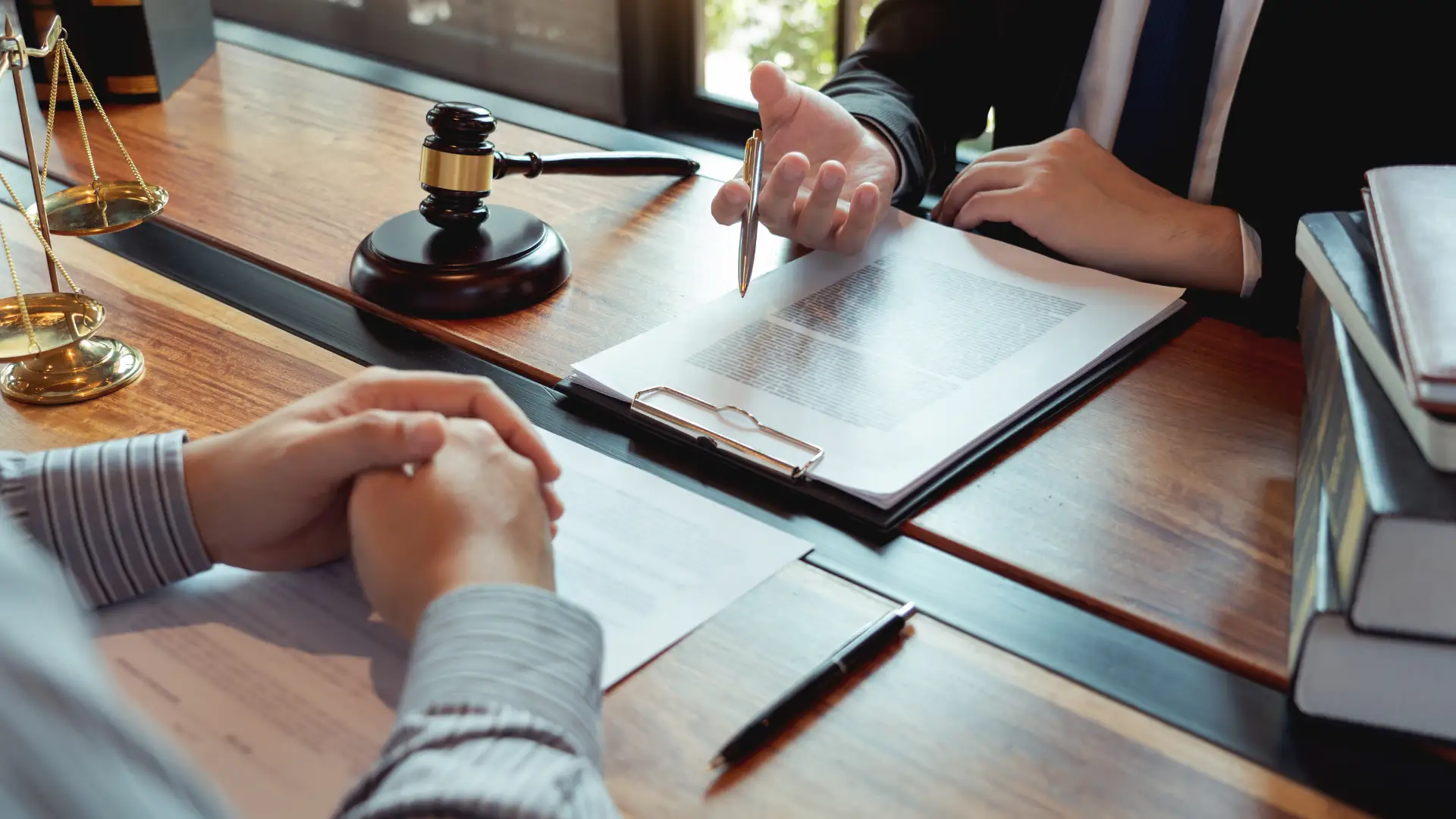 Lawyer discussing a document with a client, with a gavel on the table.